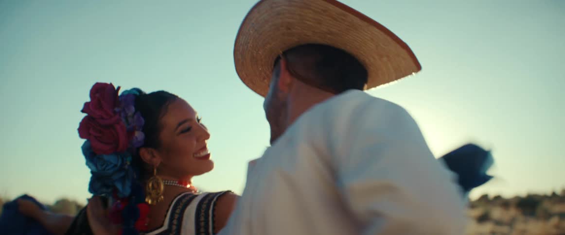Couple perform traditional dance in traditional garb under sunny sky
