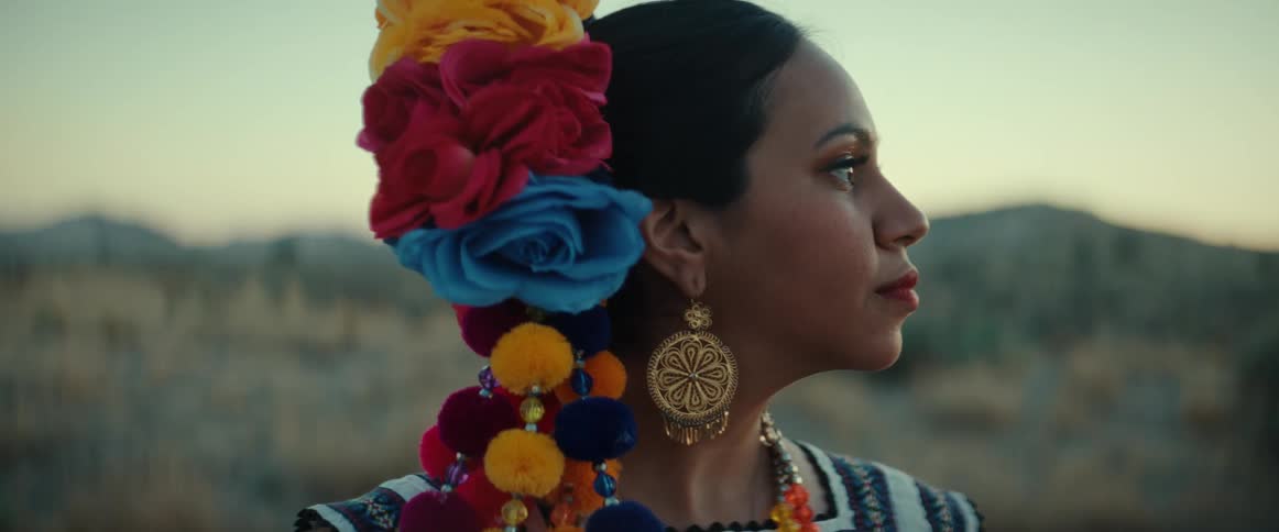 A portrait of a woman wearing a headdress and jewelry standing outdoors