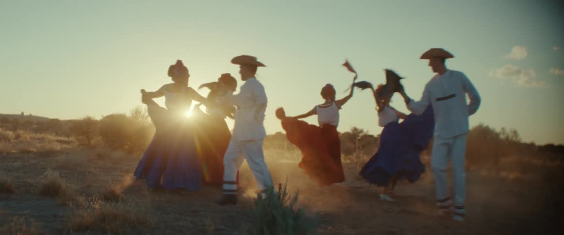 A group of Latin folk dancers perform a traditional dance in a field
