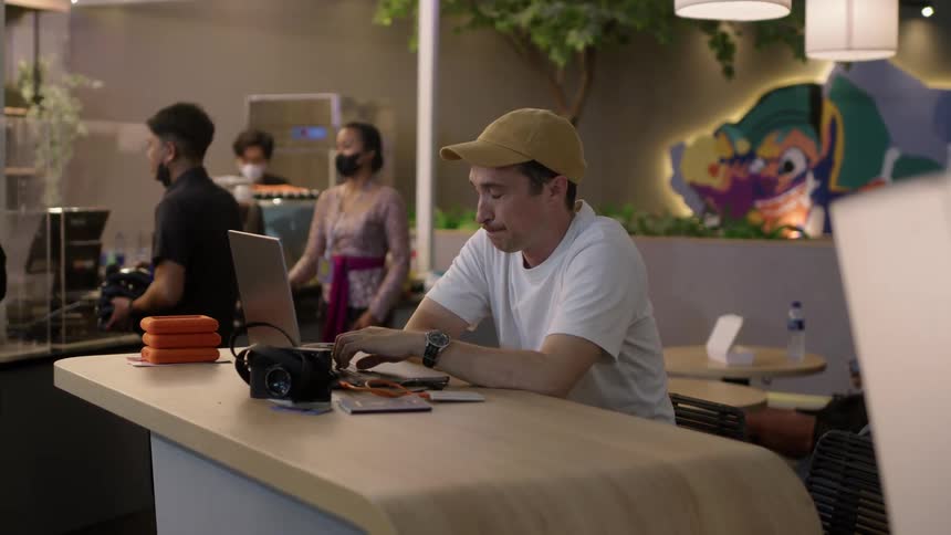 A man works on his laptop while sitting in an airport