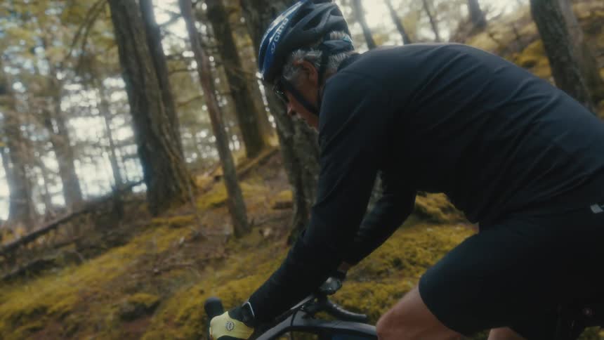 An older man climbs a challenging trail on his gravel bike