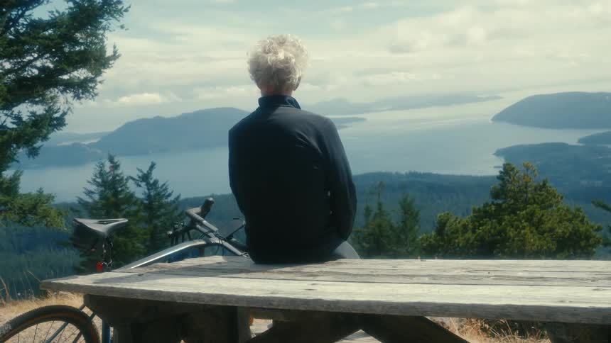 A man sits on a picnic table and takes in the view of a canyon