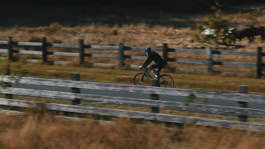 A man cycles past farmland in a rural area