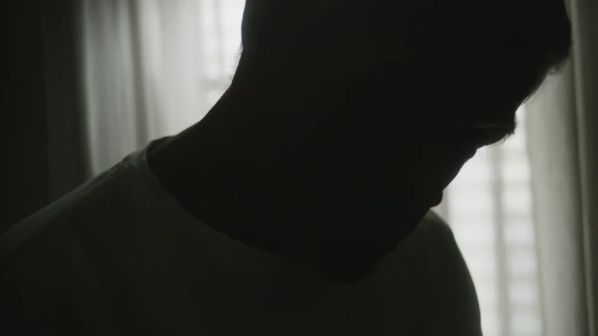 A silhouetted man sitting in a room in front of a window
