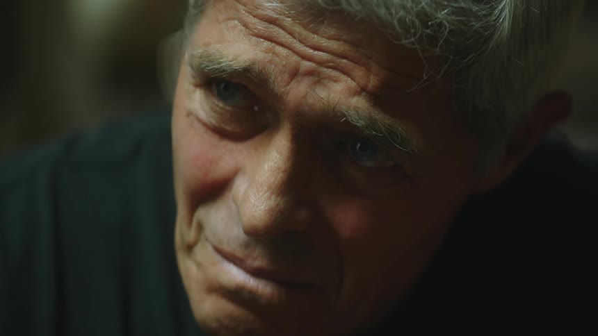 Sad man with gray hair and black sweater lifts his head up crying