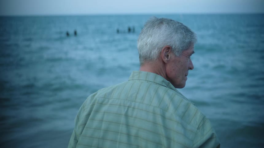 A man standing looking at the water as the ocean rolls