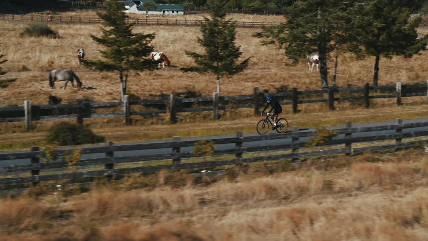 A man is riding his bicycle past the farm