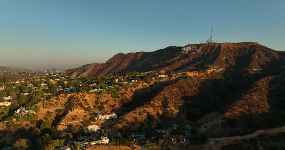 The hollywood sign on a hill with houses below