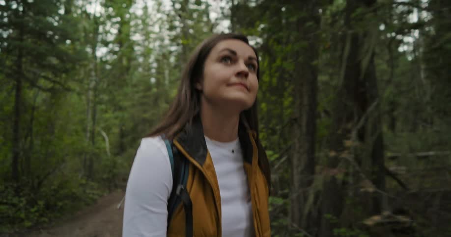 A woman hiking through a forest looks around