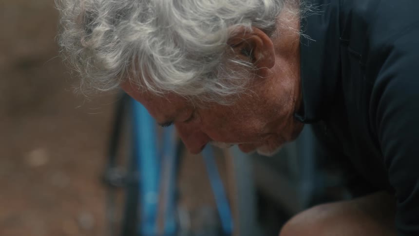 A man sits inside his car door with his bicycle leaning against the vehicle outside