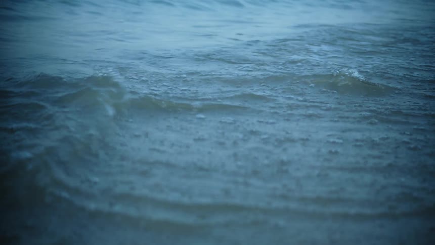 Waves roll onto beach foaming on the sand