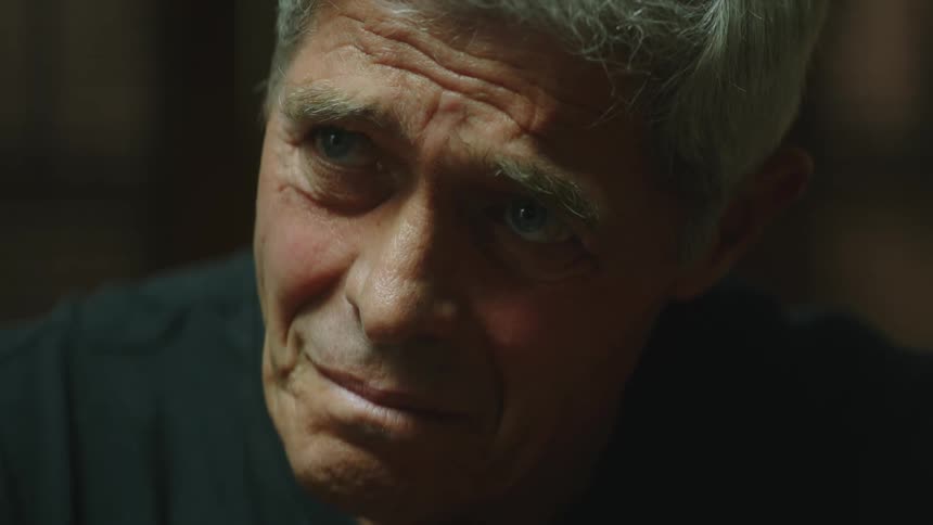 White haired elderly man frowns downcast raising his head then looking down again