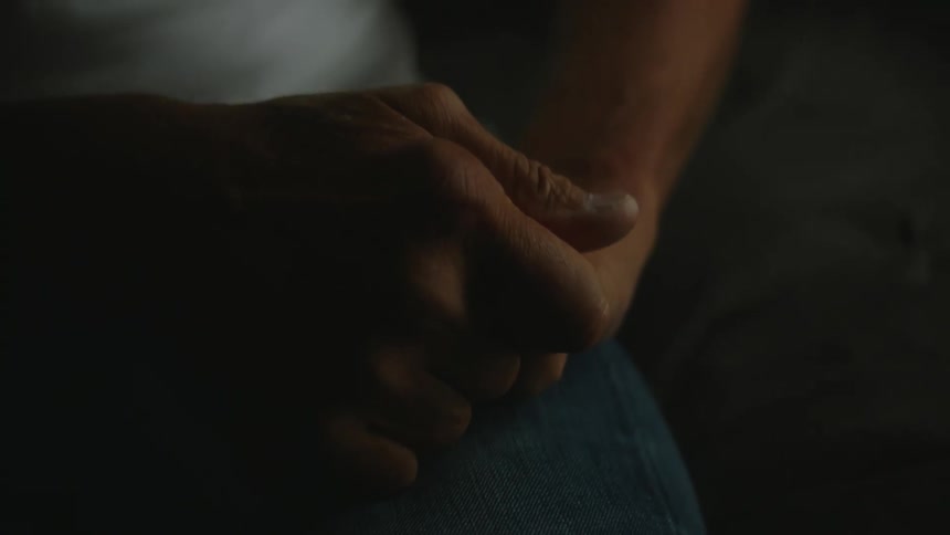 A man rubbing his hands in a dark room