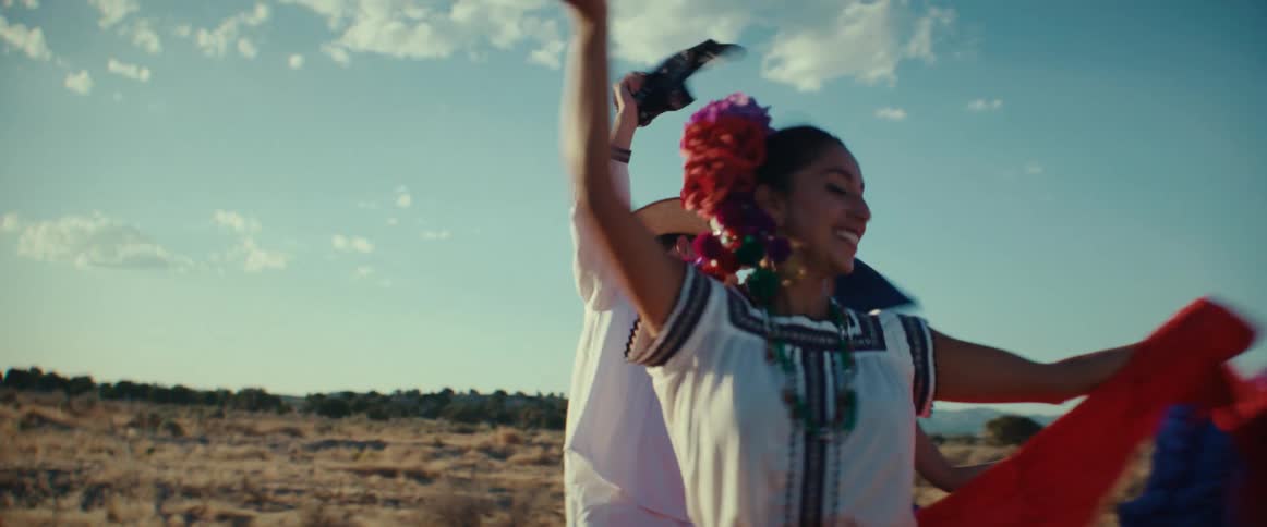 Folk dancers perform traditioned group dance in field under a sunny sky