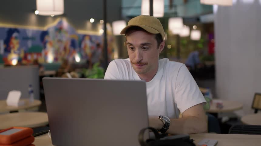 A man sitting in front of a laptop in an office yawns