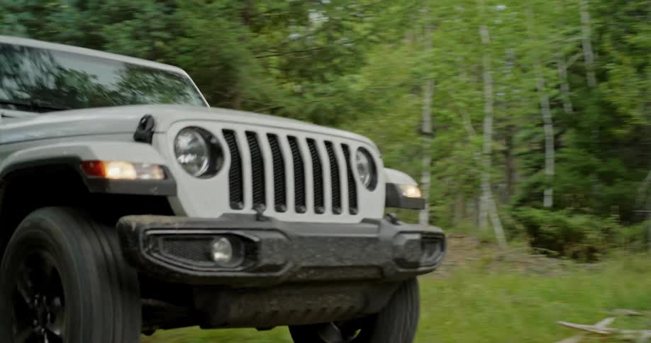 A white jeep is traveling on a forest road