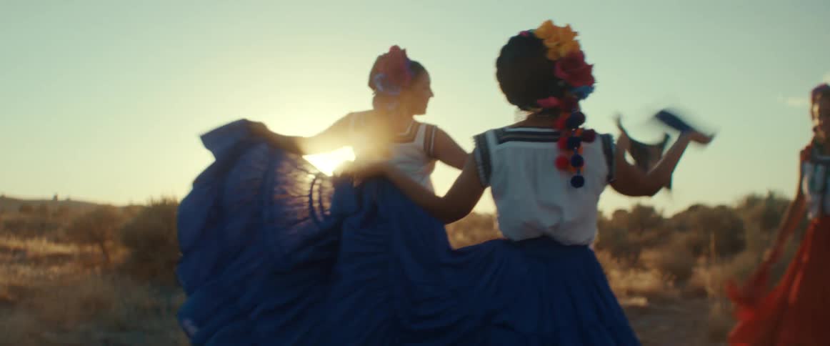A group of men and women wave flags as they dance in a field