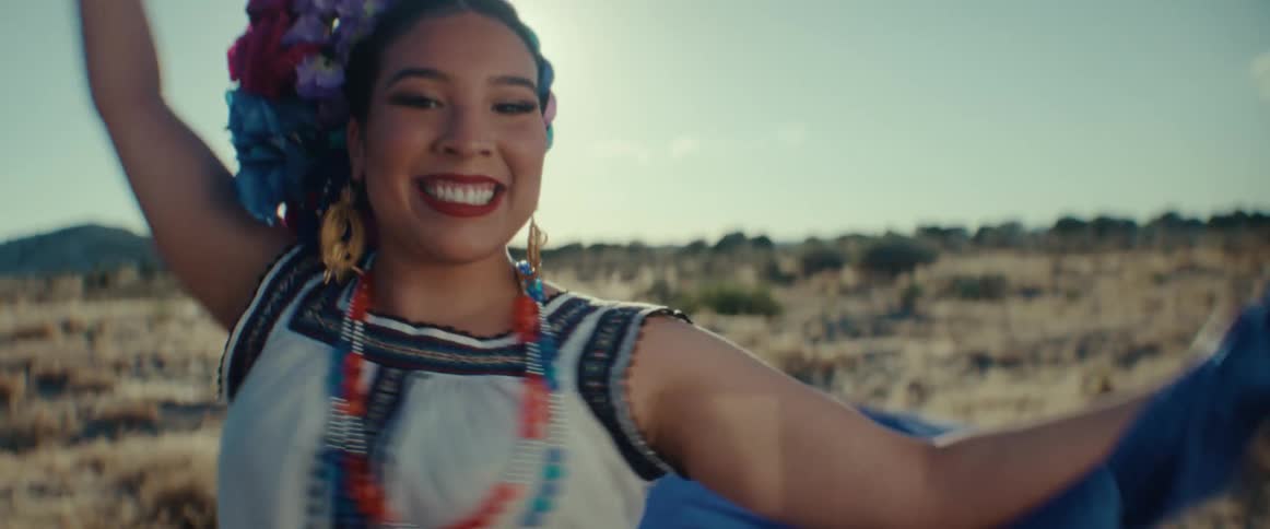 Female folk dancer spins and smiles while dancing in field on sunny day