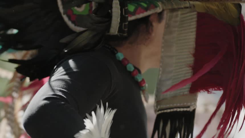 A man wearing an elaborate headdress is dancing