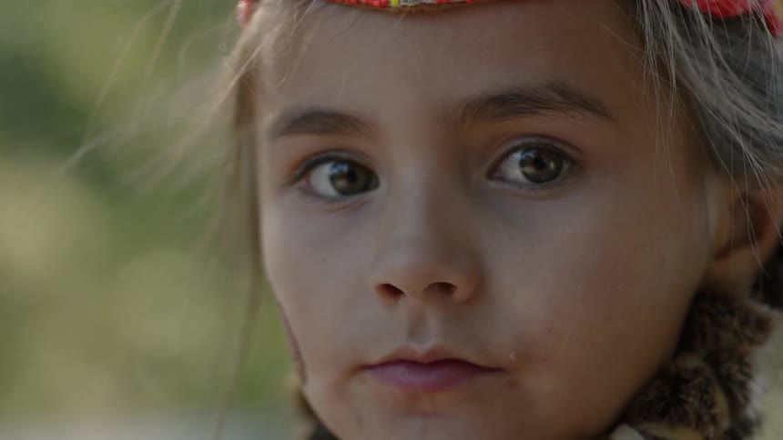 A little girl wearing an american indian headband turns toward the camera