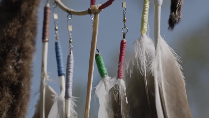 Feathers decorated with colored thread dangle in the breeze