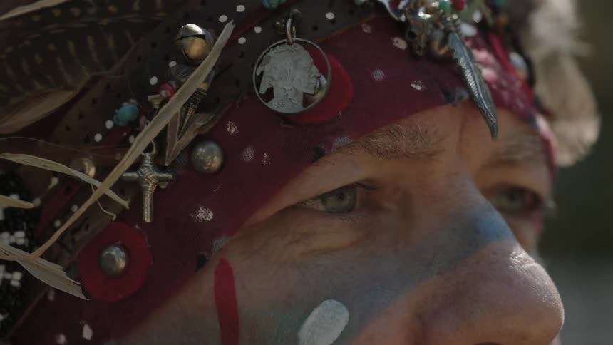 A man with a headband and face-paint stares into the distance