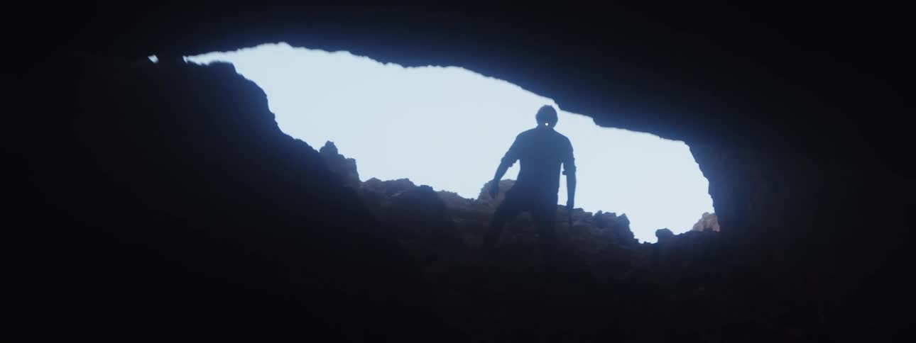 A man climbs in to a dark cave