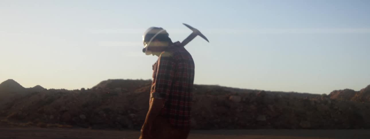 A miner is carrying a pickax