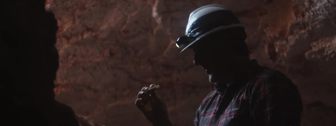The miner examines a stone in the cave