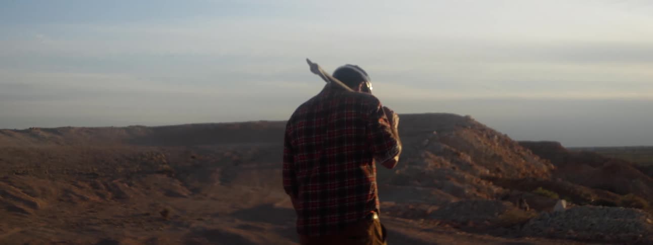 A miner is carrying a pickax on his shoulder