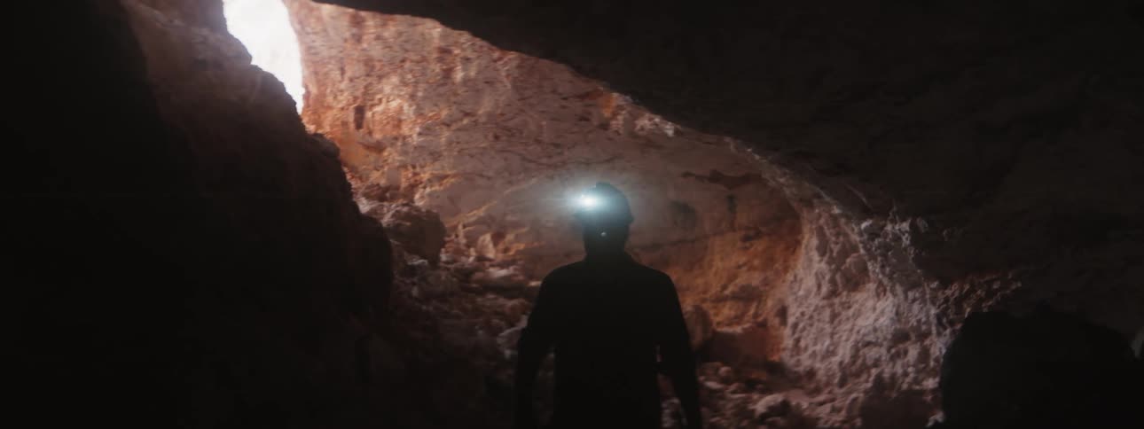 A man climbs in to a dark cave