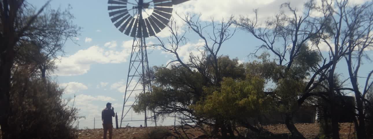 A man walks up a hill toward a windmill