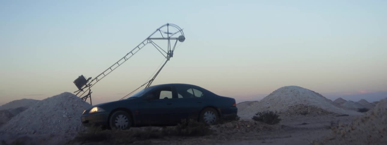 A person drives a vehicle through a construction site and mounts of gravel