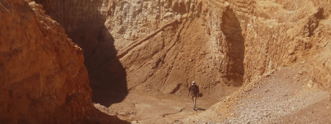 A man carries a shovel in a desert area