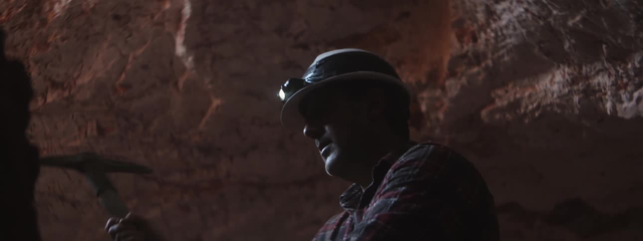 A man mining for rock with a pick axe