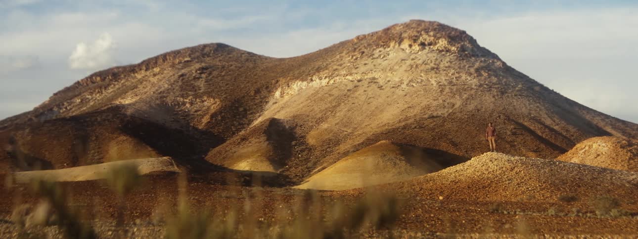 A man is standing on a hill in the distance