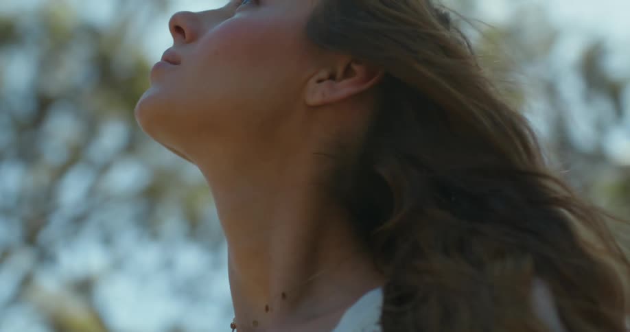A woman looks up at trees