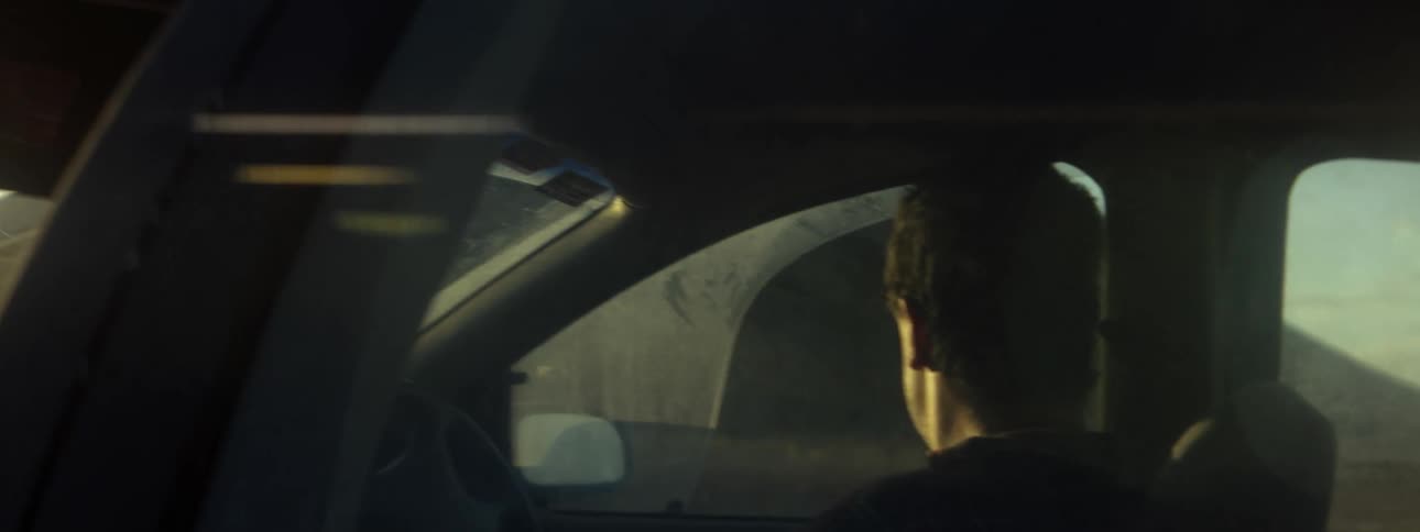 The sun shines on a mans face as he drives an automobile