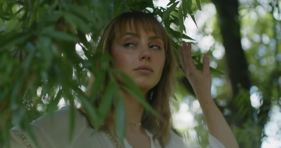 A woman looks around as she walks through trees