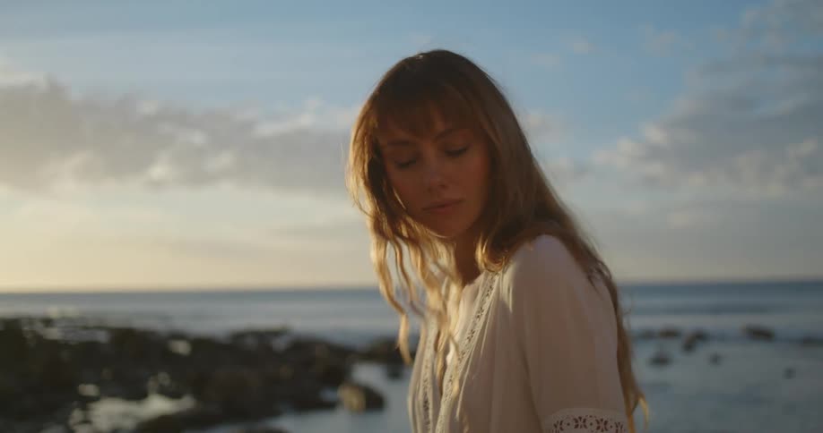 Woman walks along shore with ocean in the background