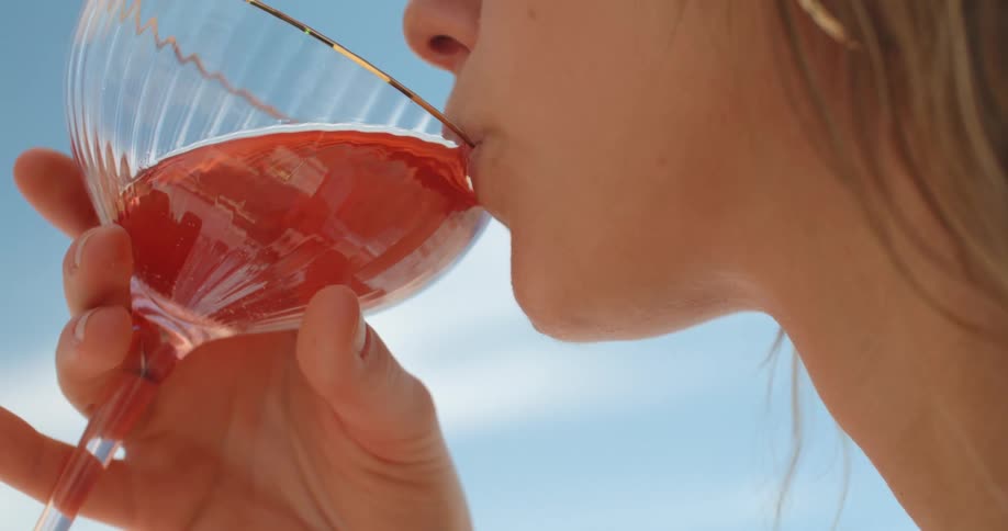 A woman sips a cocktail while standing outside