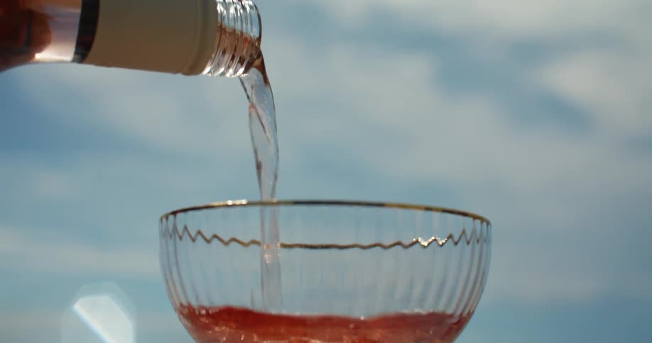 A woman holds a glass and pours wine in to it
