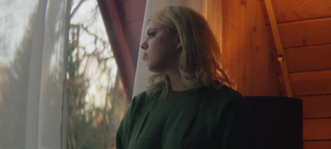 A woman is looking out the window at home