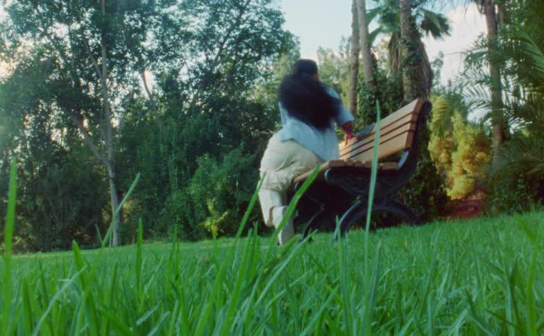 A woman dances on a park bench