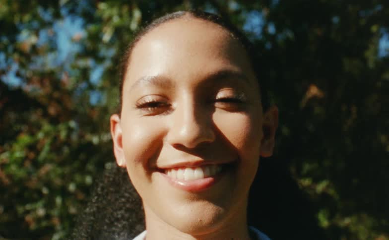 A woman smiles while posing in front of a tree
