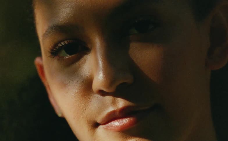 Close up of the face of a young woman under shadows caught on vintage film looking at the camera