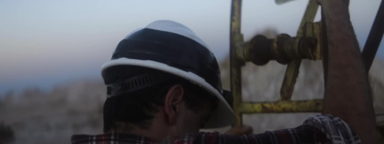 A man climbs down into a hole below an oil well