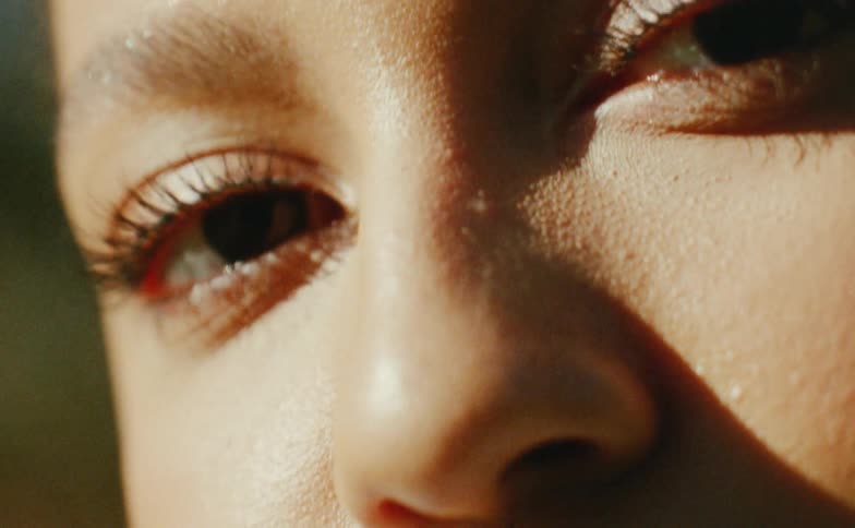 The sun shines on the face of a teenage girl as she blinks her eyes