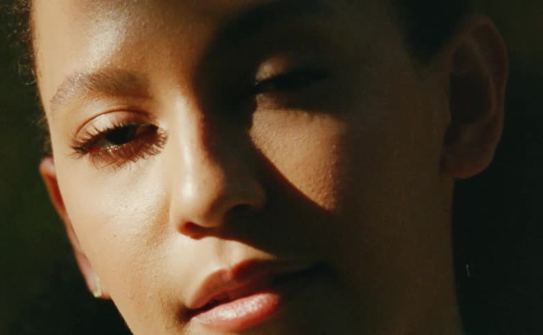 Close up of the face of a young woman under shadows caught on vintage film looking at the camera