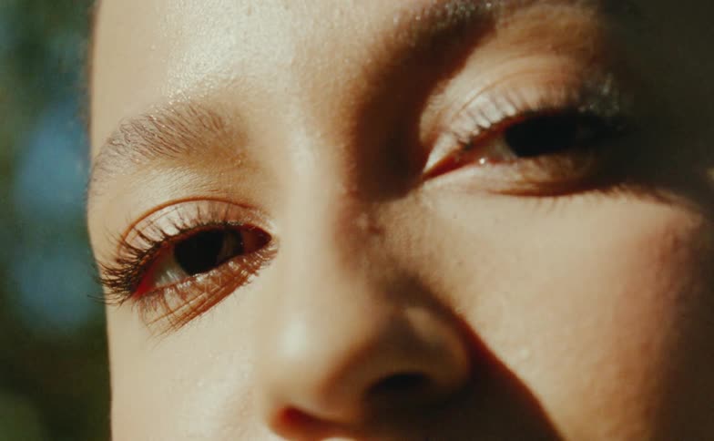 Close up of the face of a young woman under shadows caught on vintage film looking at the camera